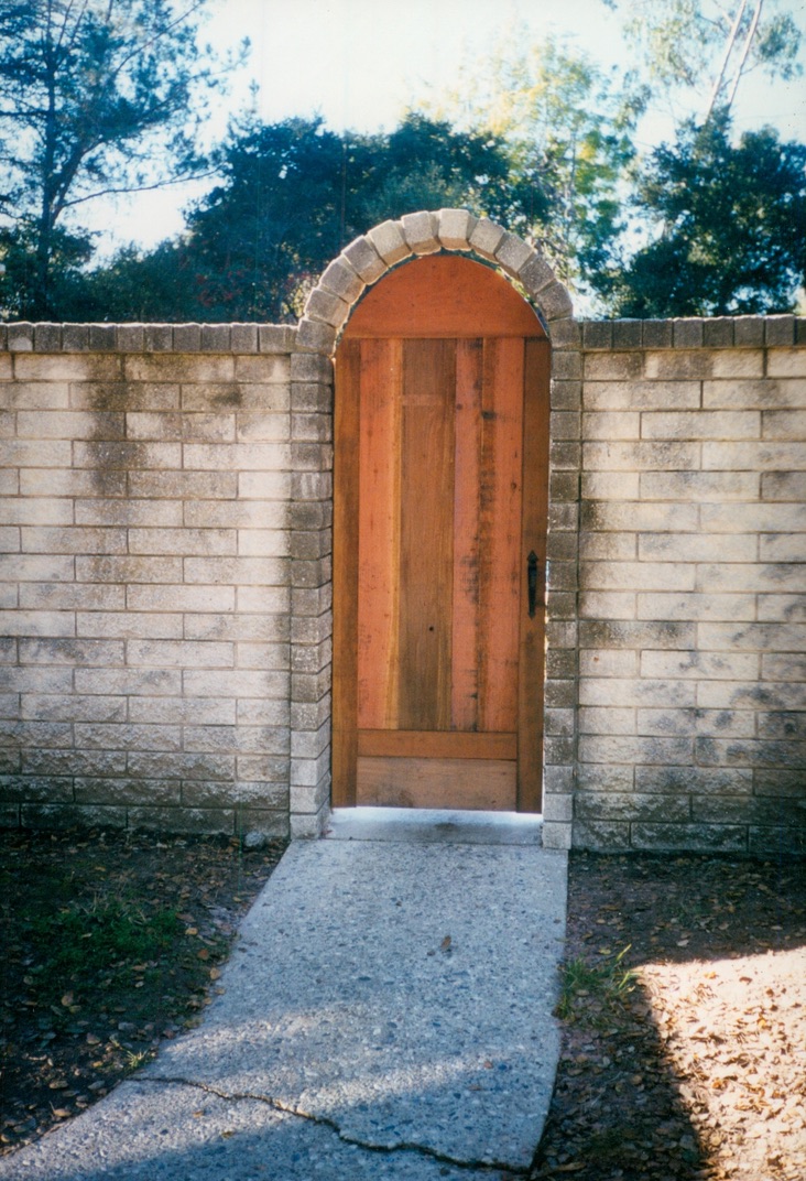 Arched wood garden gate set into a privacy fence, creating a decorative and secure entryway.