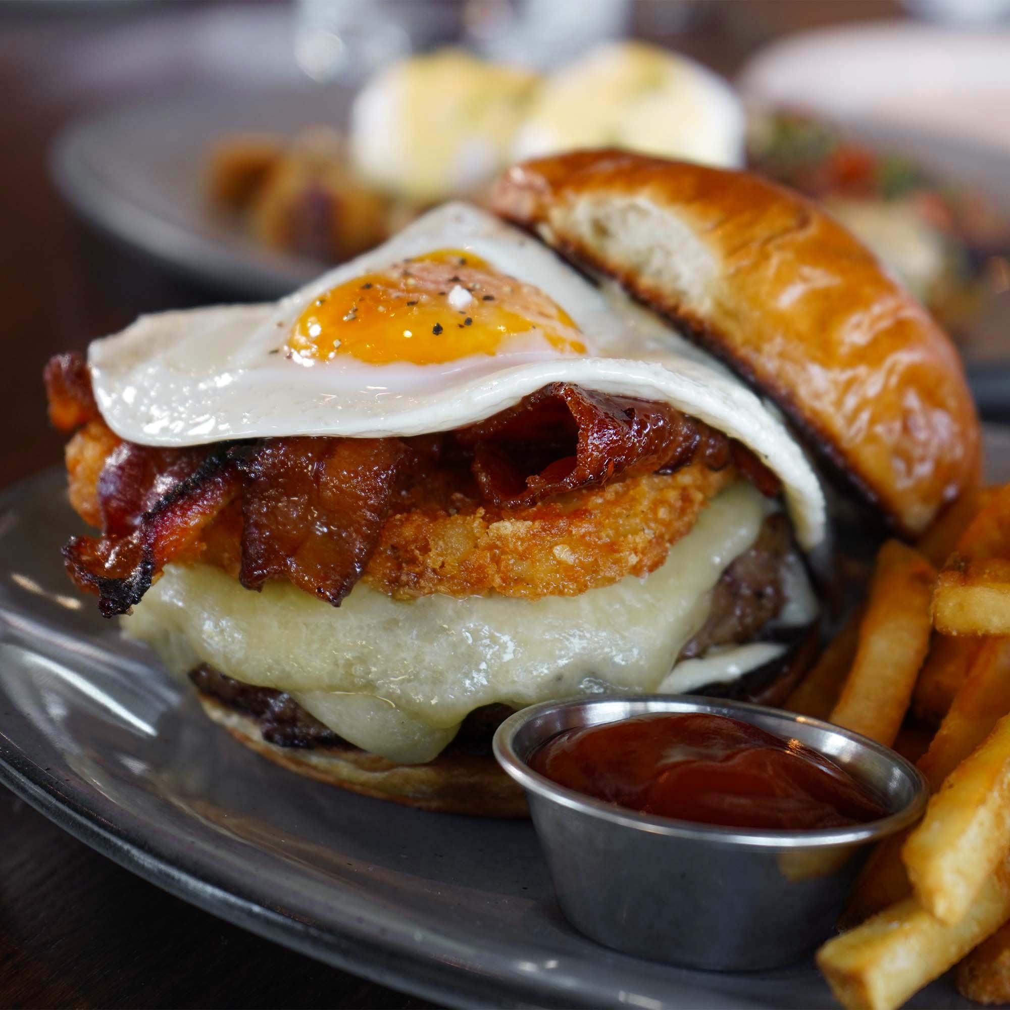 Allen brothers angus beef, fried egg, candied bacon, potato rosti, cheddar, garlic aioli, brioche bun, french fries.