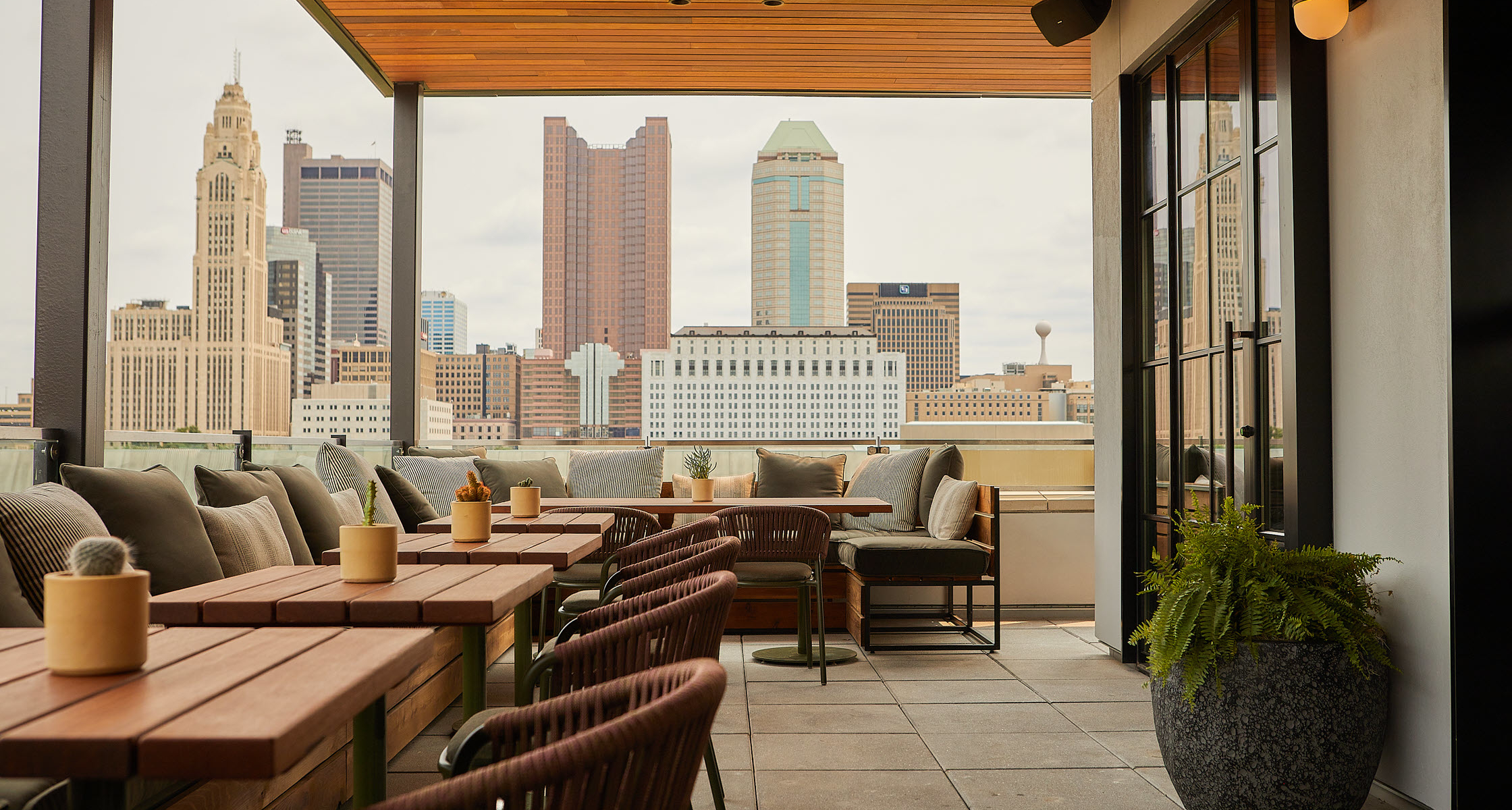 Brass Eye rooftop bar at The Junto, with covered terrace seating and views across the Columbus skyli 
