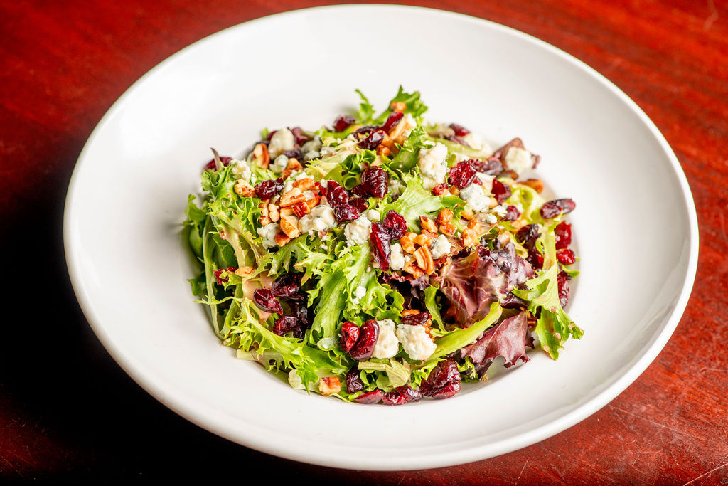 Cranberry Pecan Salad: mixed greens, dried cranberries, blue cheese crumbles, sweet roasted pecans, signature orange-cranberry splash dressing