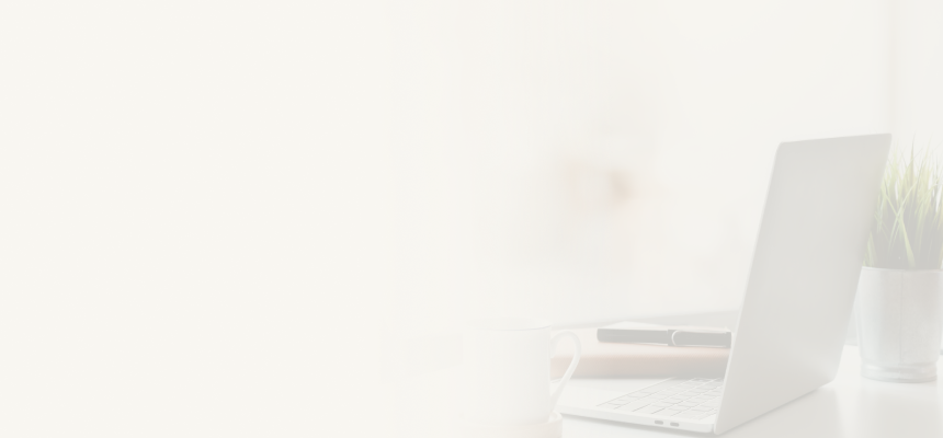 An open laptop, notebook, pen, and mug on a desk.