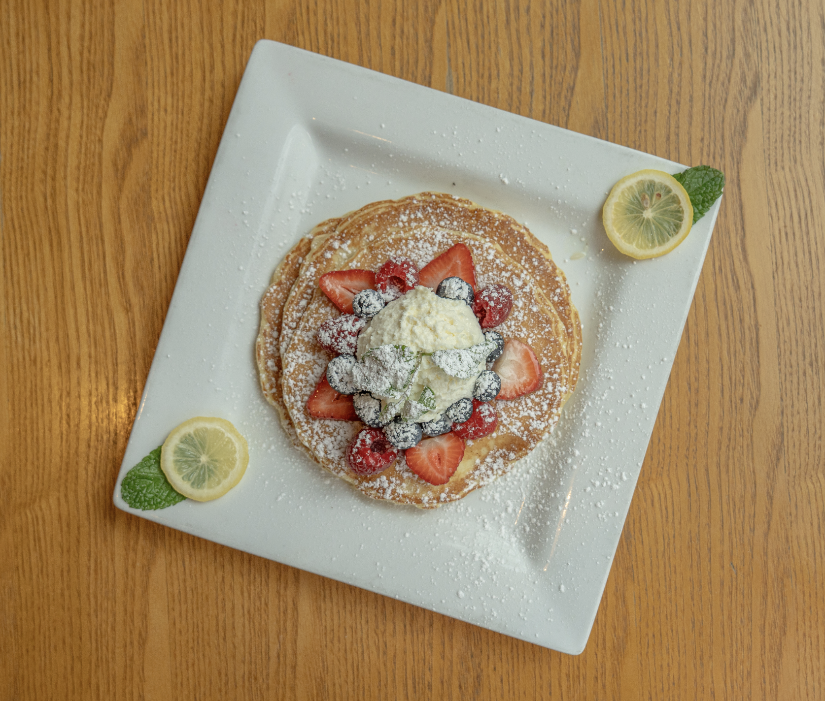 Our lemon ricotta, pancakes are topped with blueberries, raspberries, strawberries, and homemade lemon, Devonshire cream.