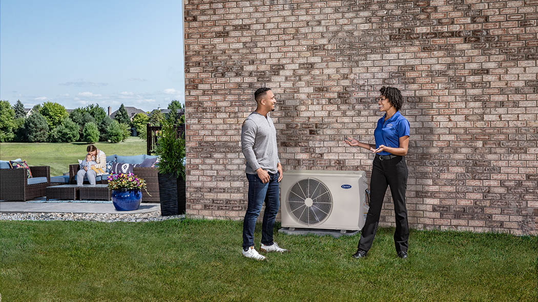 A Carrier dealer talking to a homeowner outside after performing a ductless installation