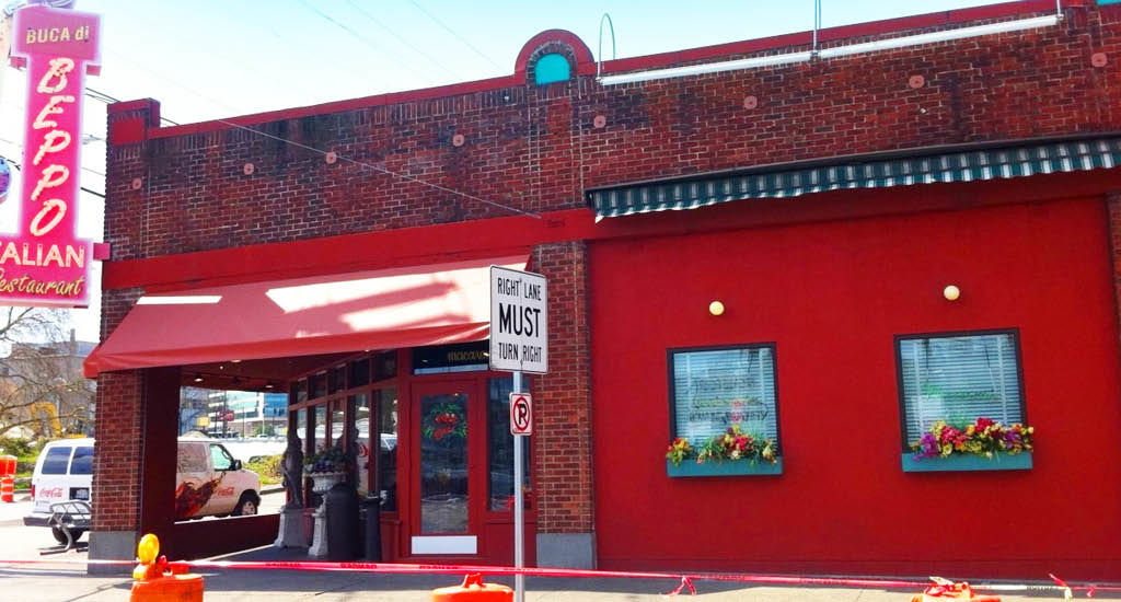 Side view of Buca di Beppo Seattle restaurant showing red walls and windows with flowers on the ledge.