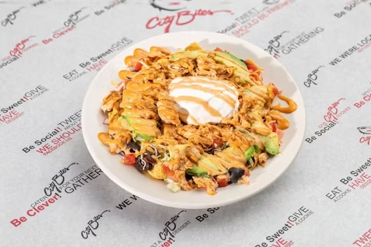 Fritos® corn chips, grilled chicken, shredded lettuce, tomatoes, red onions, black olives, shredded cheddar, topped with sour cream, sliced avocado, and chipotle sauce.