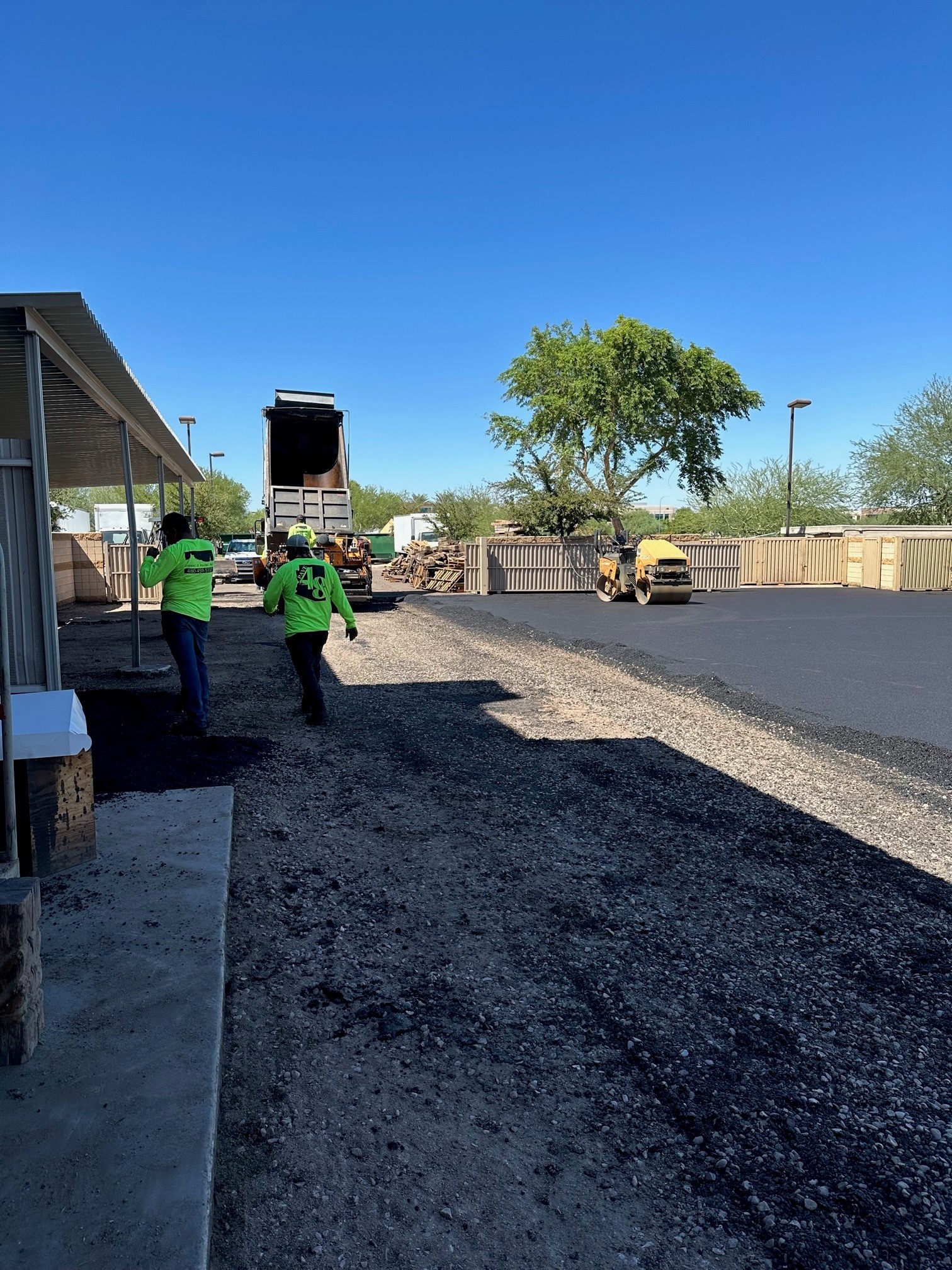 Our red crew hard at work laying new asphalt at a business/Chandler, Arizona/Contact Pinnacle Paving to get your free estimate