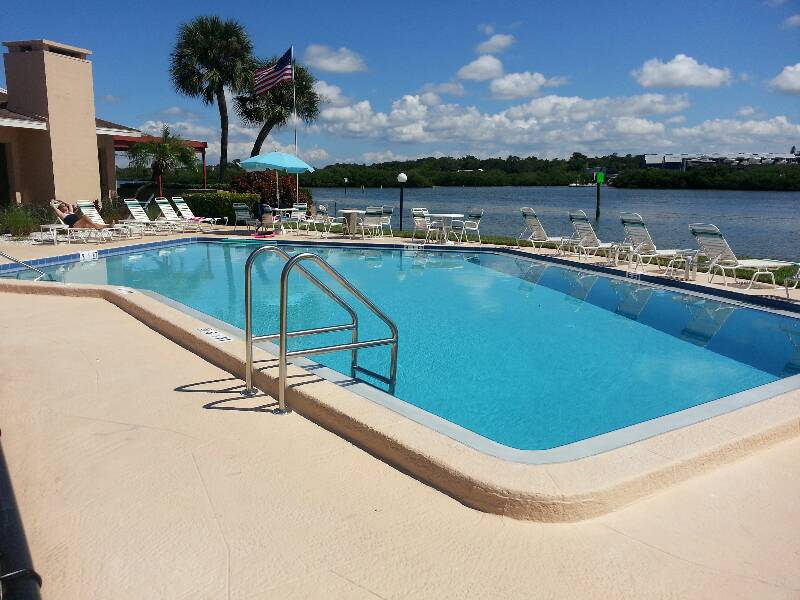 Custom inground swimming pool featuring crystal-clear blue water, smooth coping edges, and a light-colored paver patio surround.