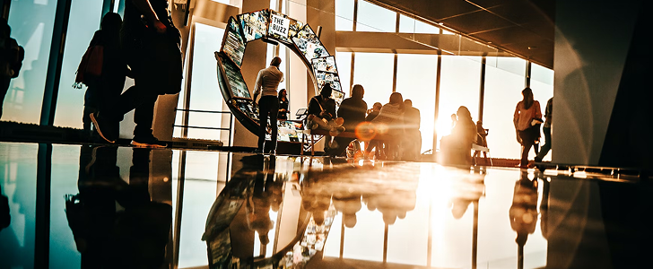 The interior of a modern office setting with the setting sun shining through the windows.