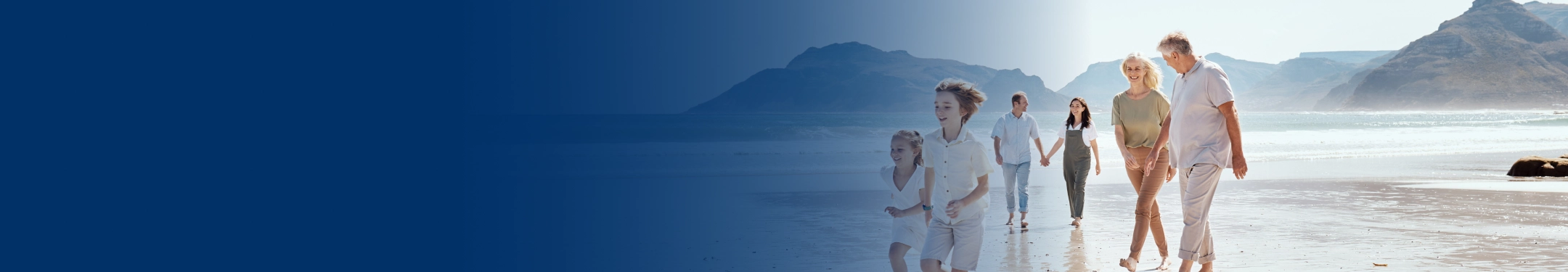 A multigenerational family walking along the beach together.