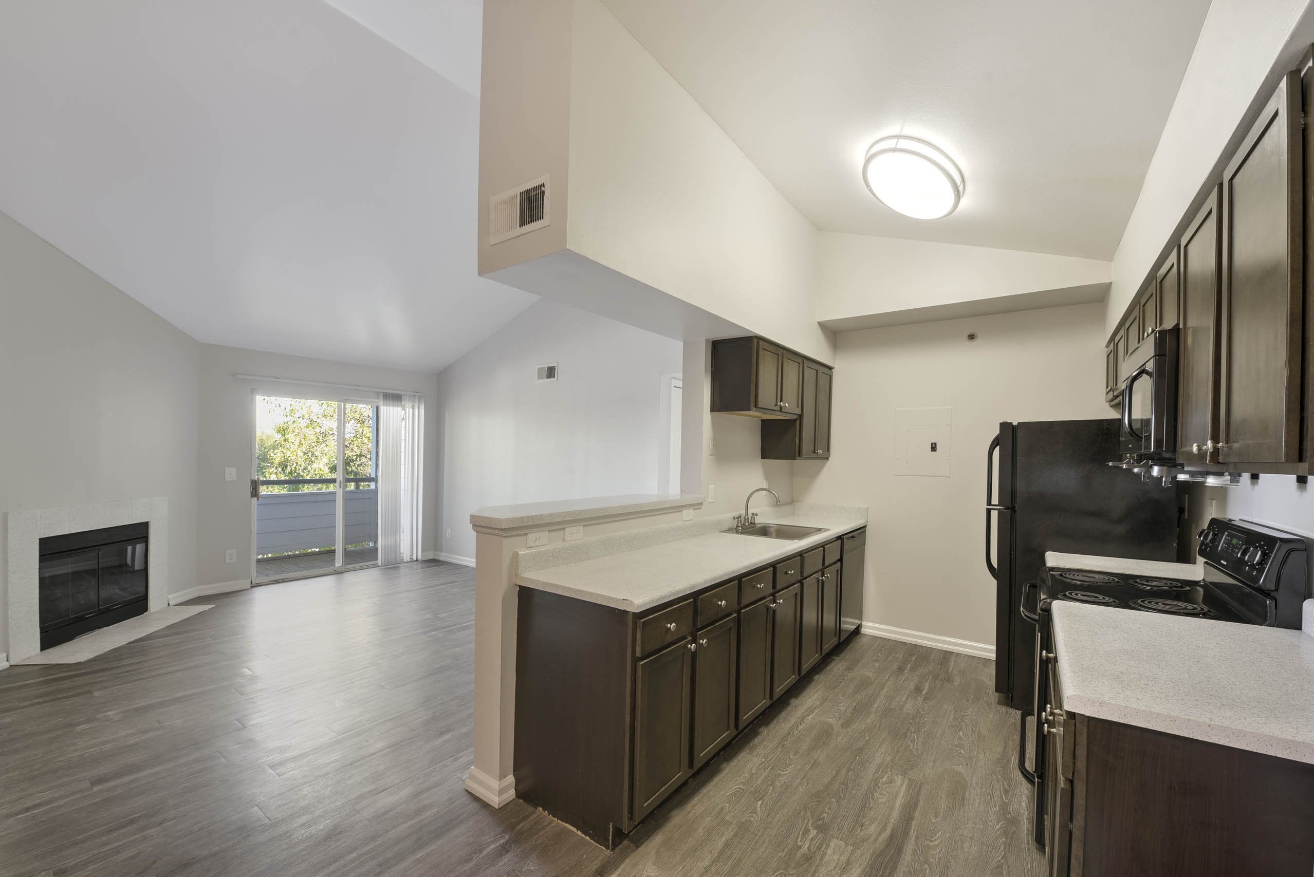 A modern kitchen with dark wood floors and stainless steel appliances. 