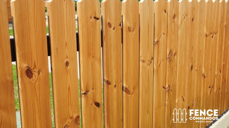 Close-up of natural pine dog-ear wood fence pickets showing detailed wood grain.
