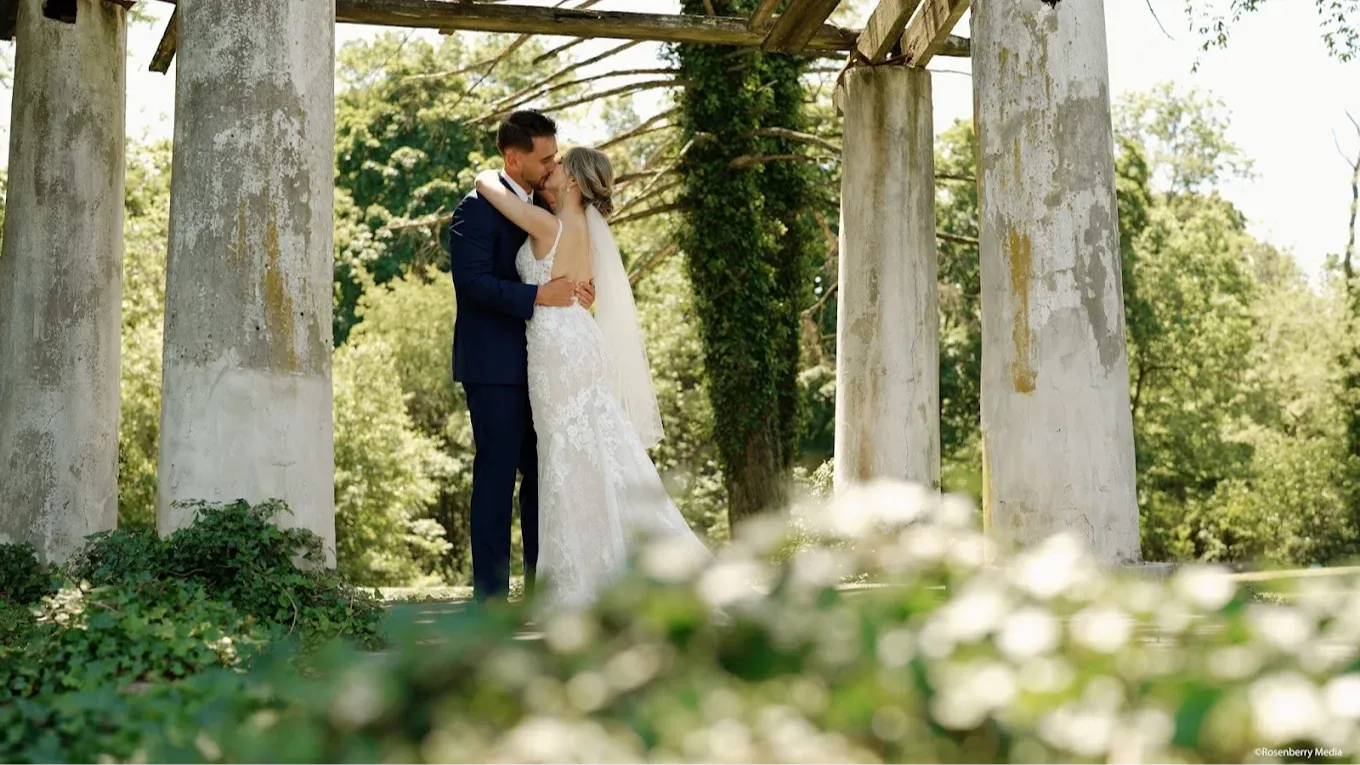 wedding photo of bride hugging groom at an overgrown arch way or bridge.