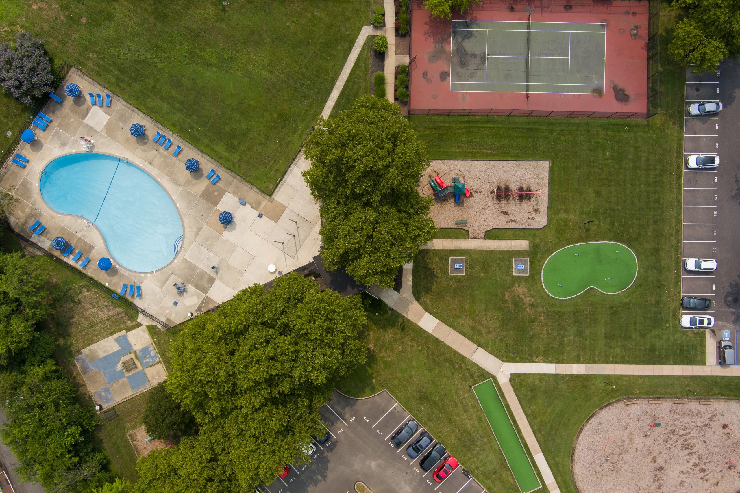 A park with a tennis court, a basketball court, a swimming pool, and a playground 