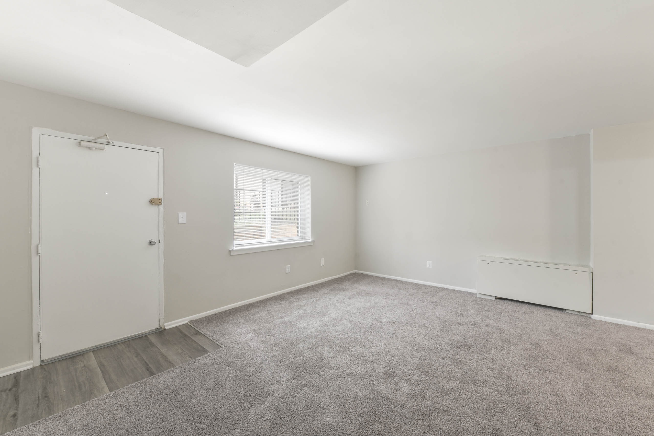 A room with a carpeted floor and a window.