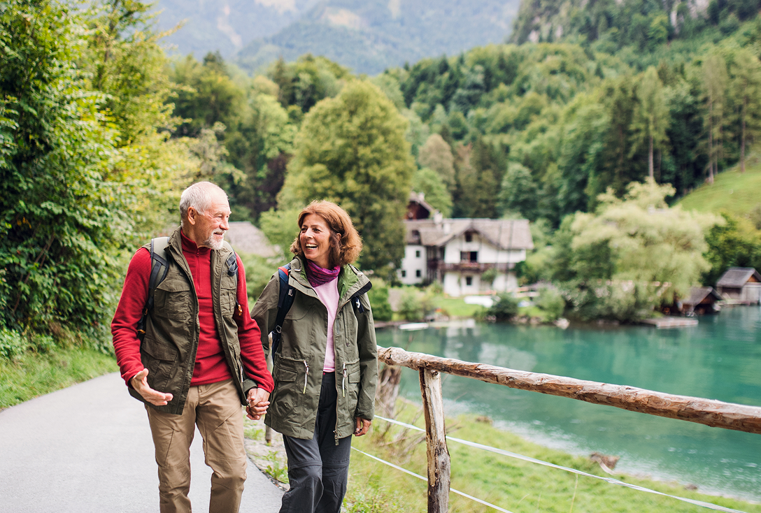 A senior couple hiking in nature, holding hands.