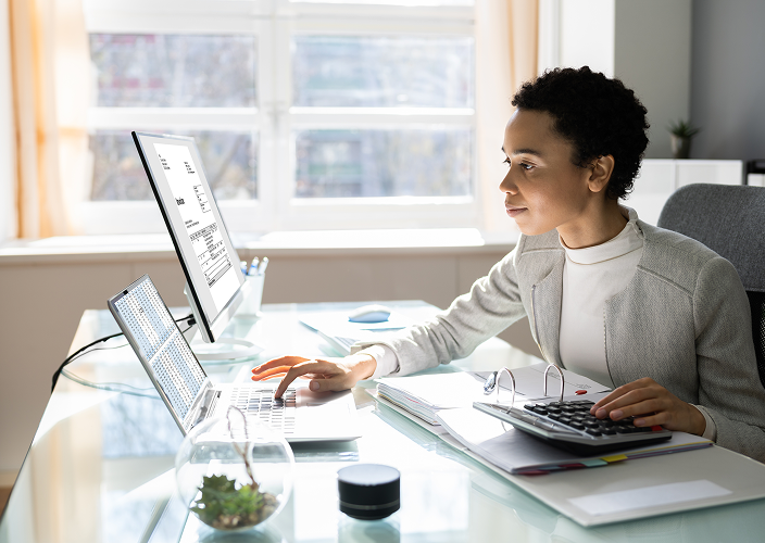 A professional woman reviewing documents on her computer in her office.
