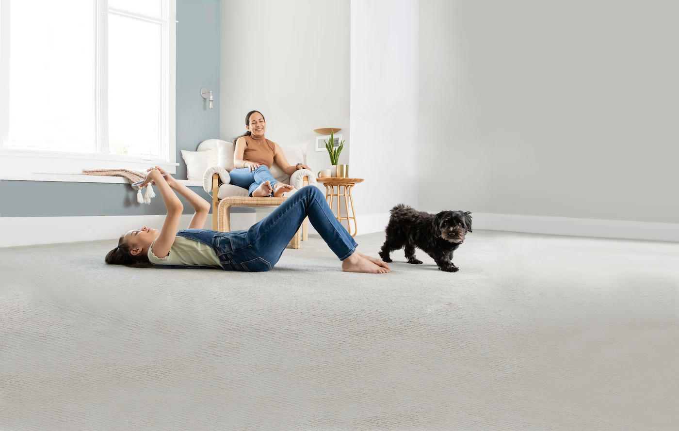 girl laying with a dog on a carpet with a woman sitting on upholstered furniture on Long Island
