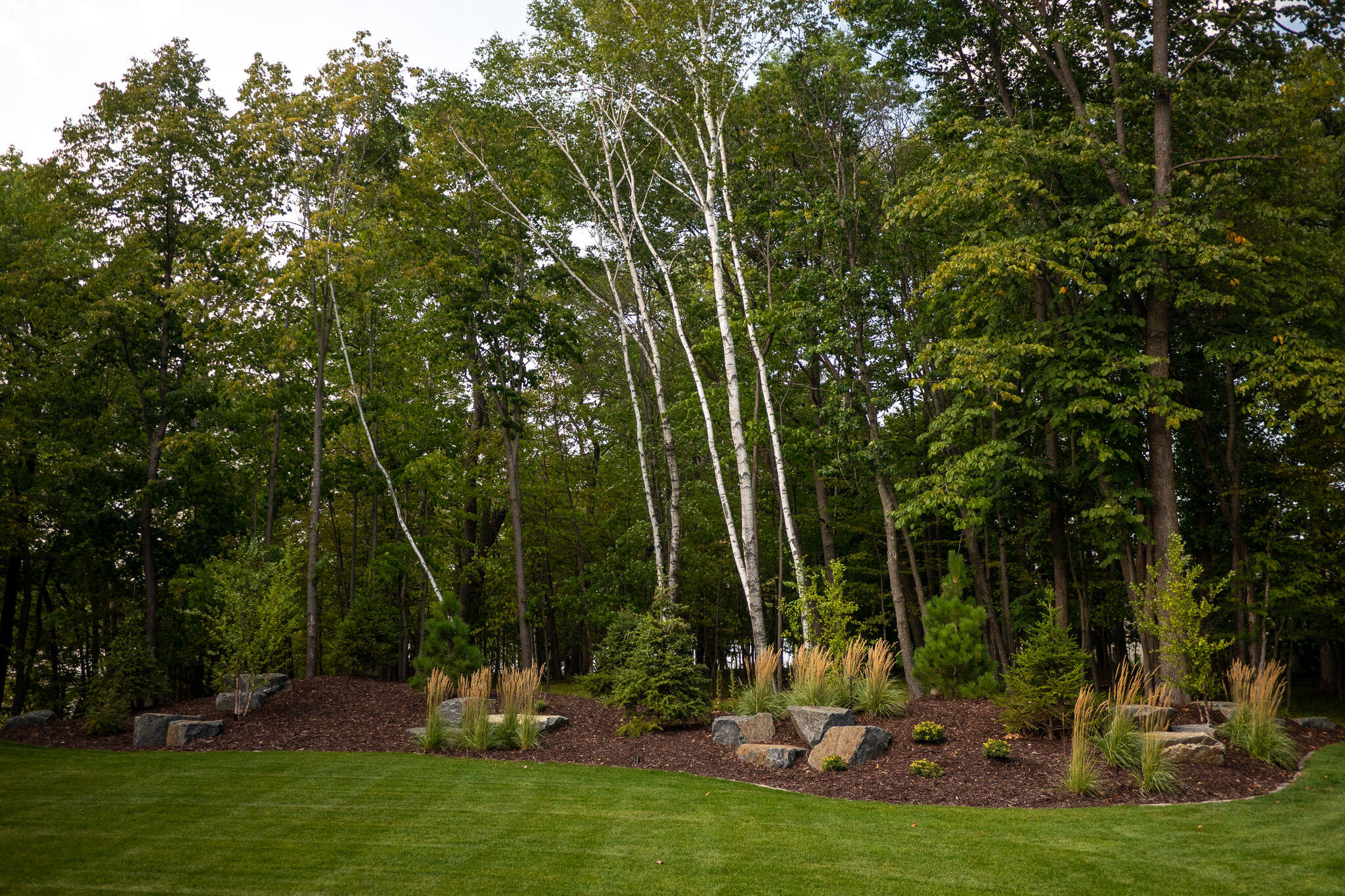 This recent project was one of our favorite ones yet. We kept the roadside landscaping minimalistic, yet polished, with the mature trees framing this incredible lake home. With the addition of fresh mulch, shrubbery, and decorative rock, the roadside landscaping makes a great first impression.
