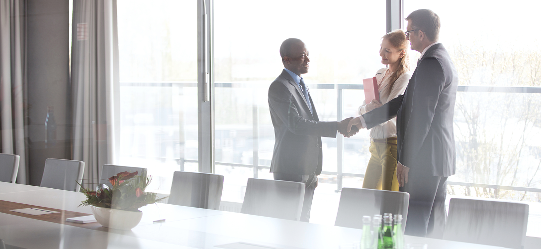 Wealth professionals shaking hands in a boardroom.