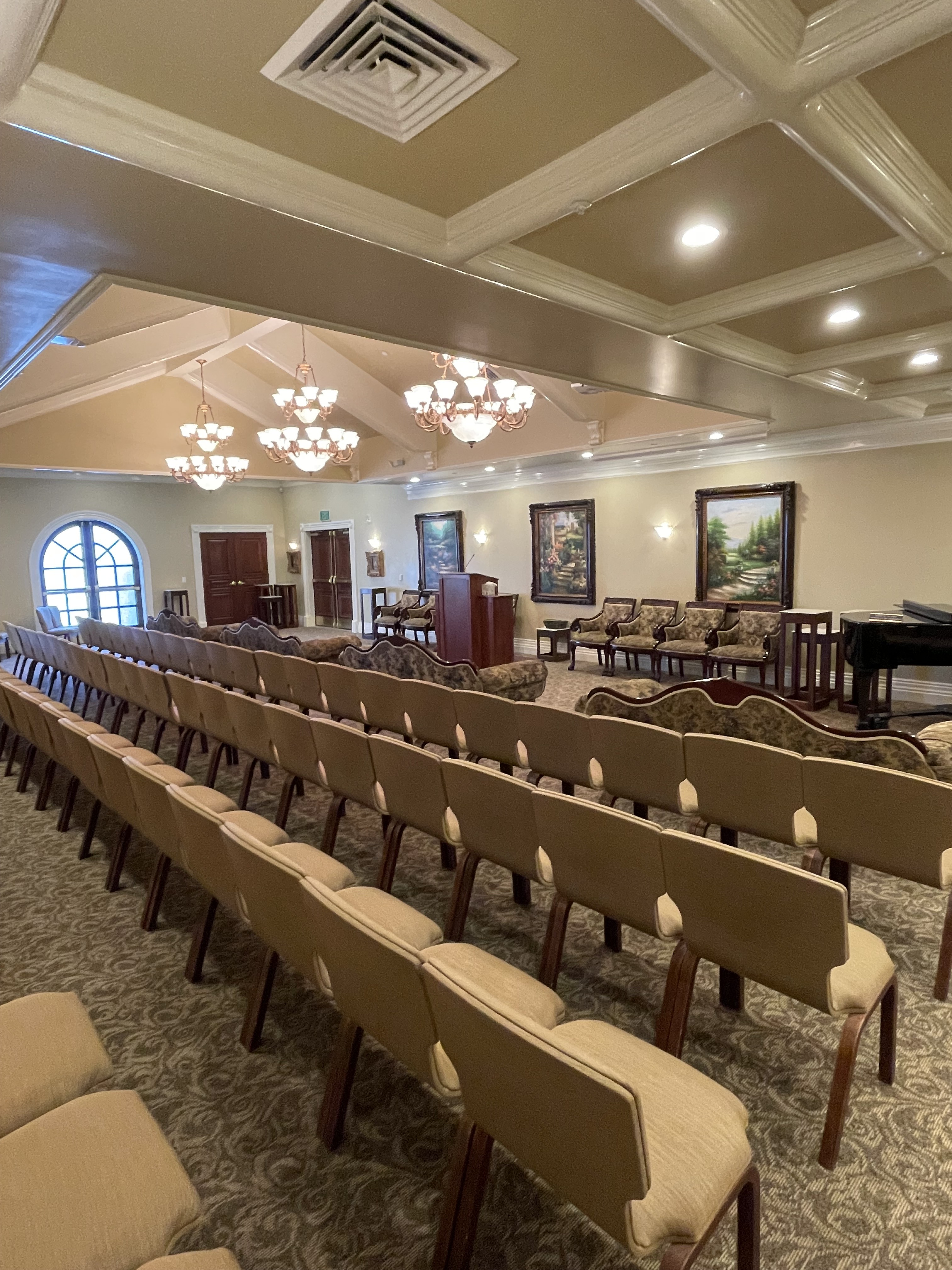 The French-style chapel at Larkin Sunset Gardens in Sandy, seating a full congregation beneath a coffered ceiling and chandeliers.
