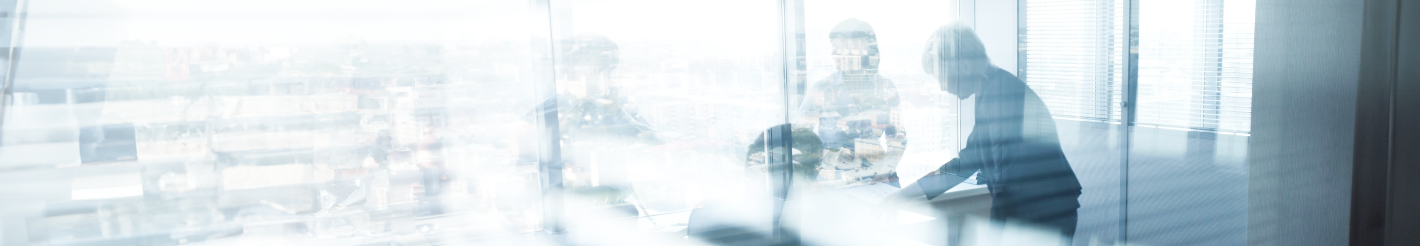 Des personnes dans une salle de réunion, vues d’une fenêtre.