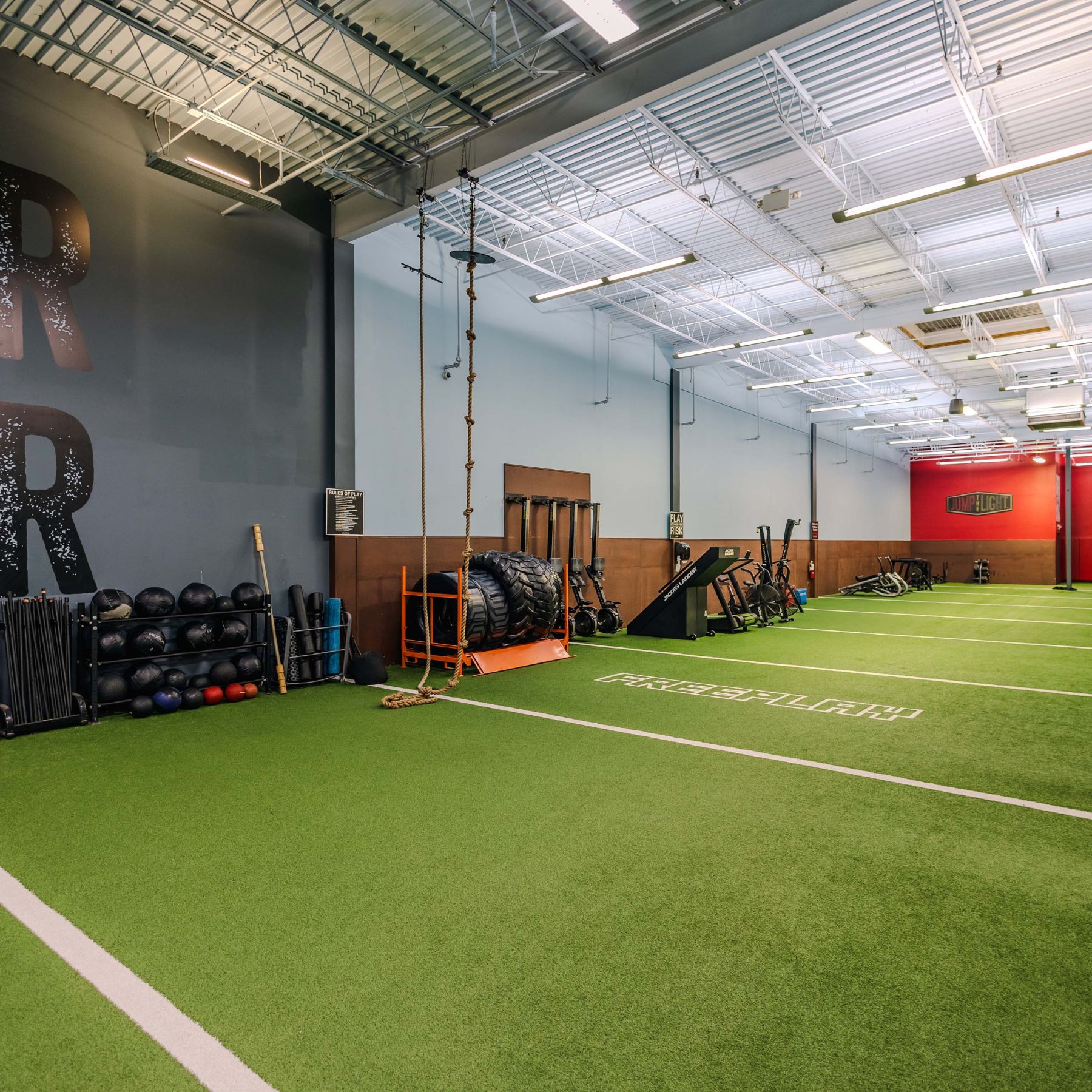 Spacious functional training zone at our Richmond gym featuring turf flooring, ropes, sleds, tires & strength training equipment.