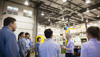A business owner addressing his employees inside a brightly lit warehouse.