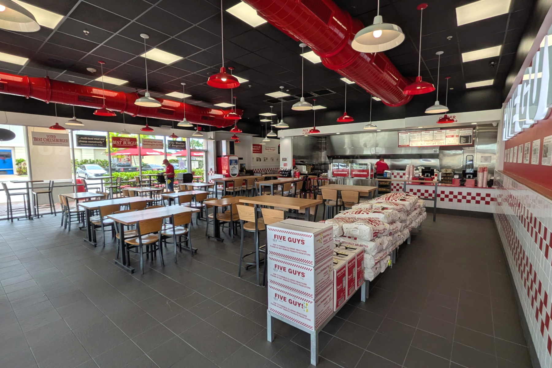 Image of the dining room of the Five Guys restaurant at 17819 Tamiami Trail in North Port, Florida. Photo shows tables, chairs and Five Guys signage.