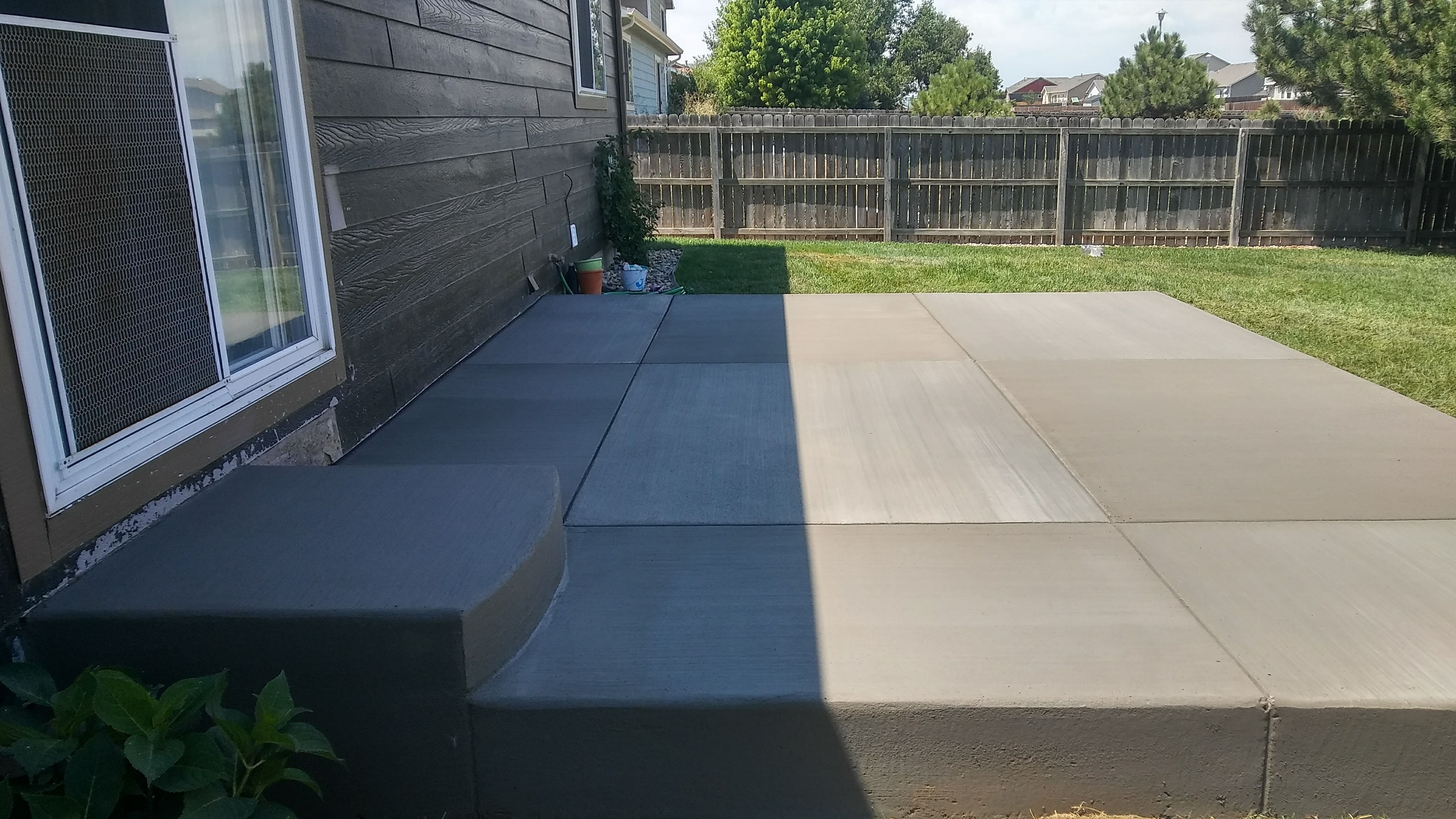 Residential concrete patio with a clean broom finish and smooth rounded edges, providing a durable outdoor area alongside the home.