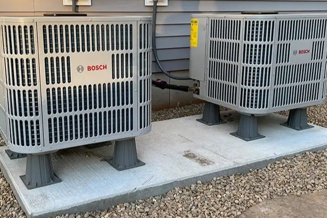 High-efficiency Bosch HVAC outdoor units installed on a concrete platform outside a residential home. These energy-efficient heating and cooling systems provide reliable climate control for year-round comfort. MAX Comfort HVAC specializes in professional HVAC installation and maintenance in Allentown, PA, ensuring optimal performance and efficiency.