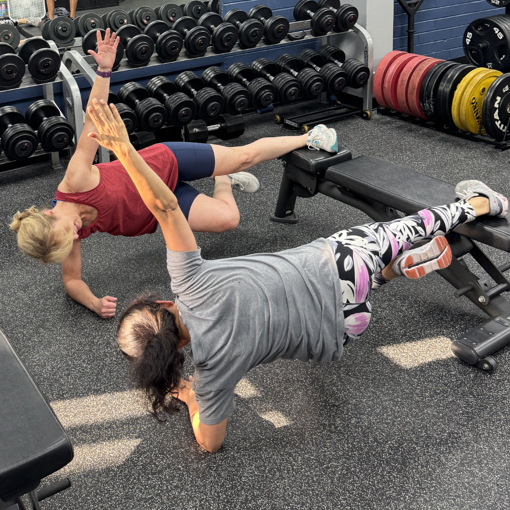 Adults performing plank exercise during small group training at Impact Sports Performance Novi