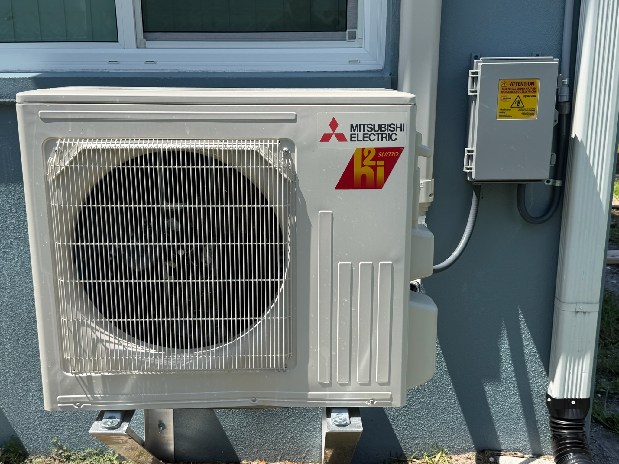 Mitsubishi Electric ductless mini-split outdoor condenser professionally mounted beside the home and 
