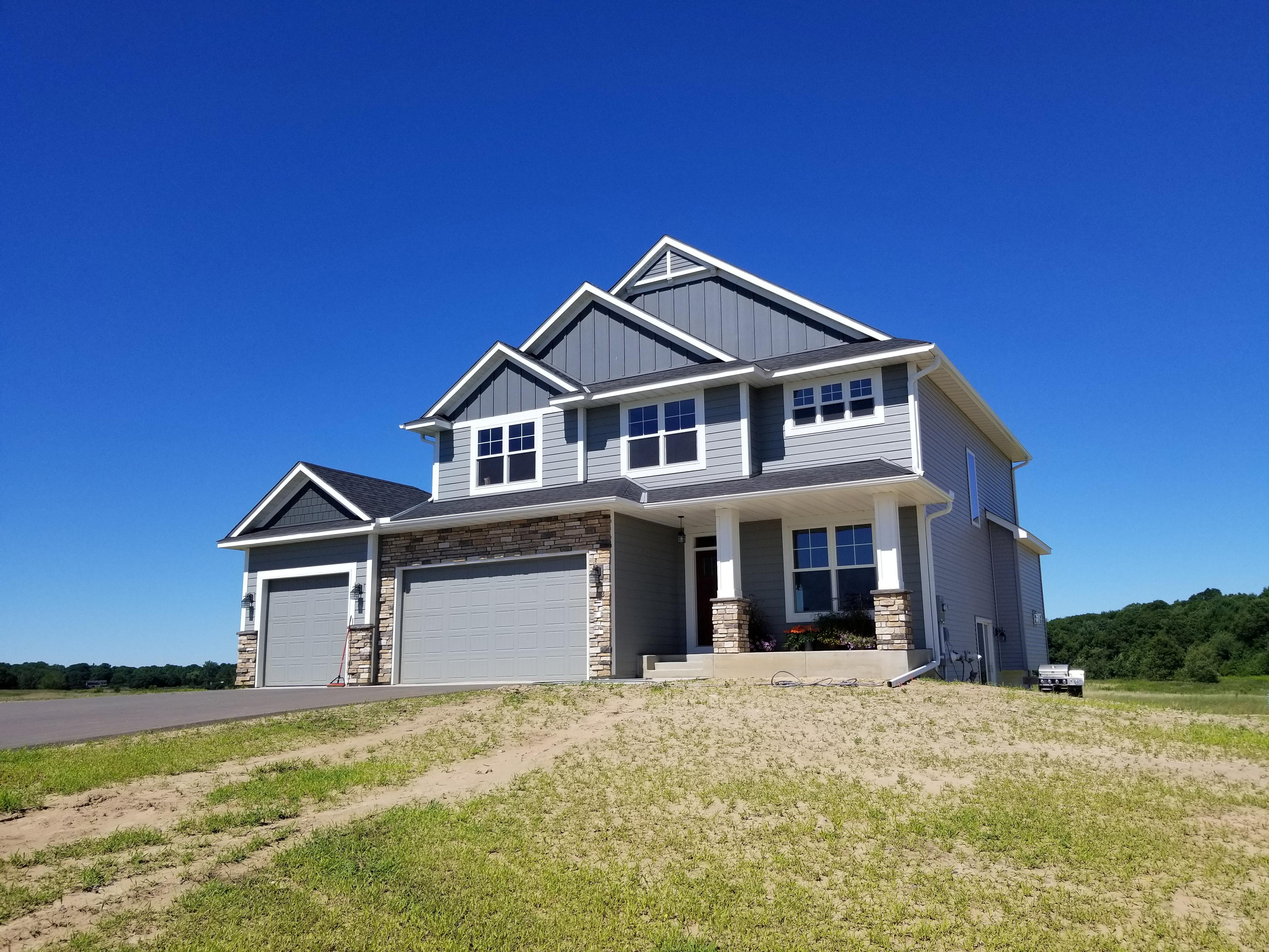 White seamless gutters and downspouts installed on a large, new construction grey home by Ultimate Gutter Solutions.