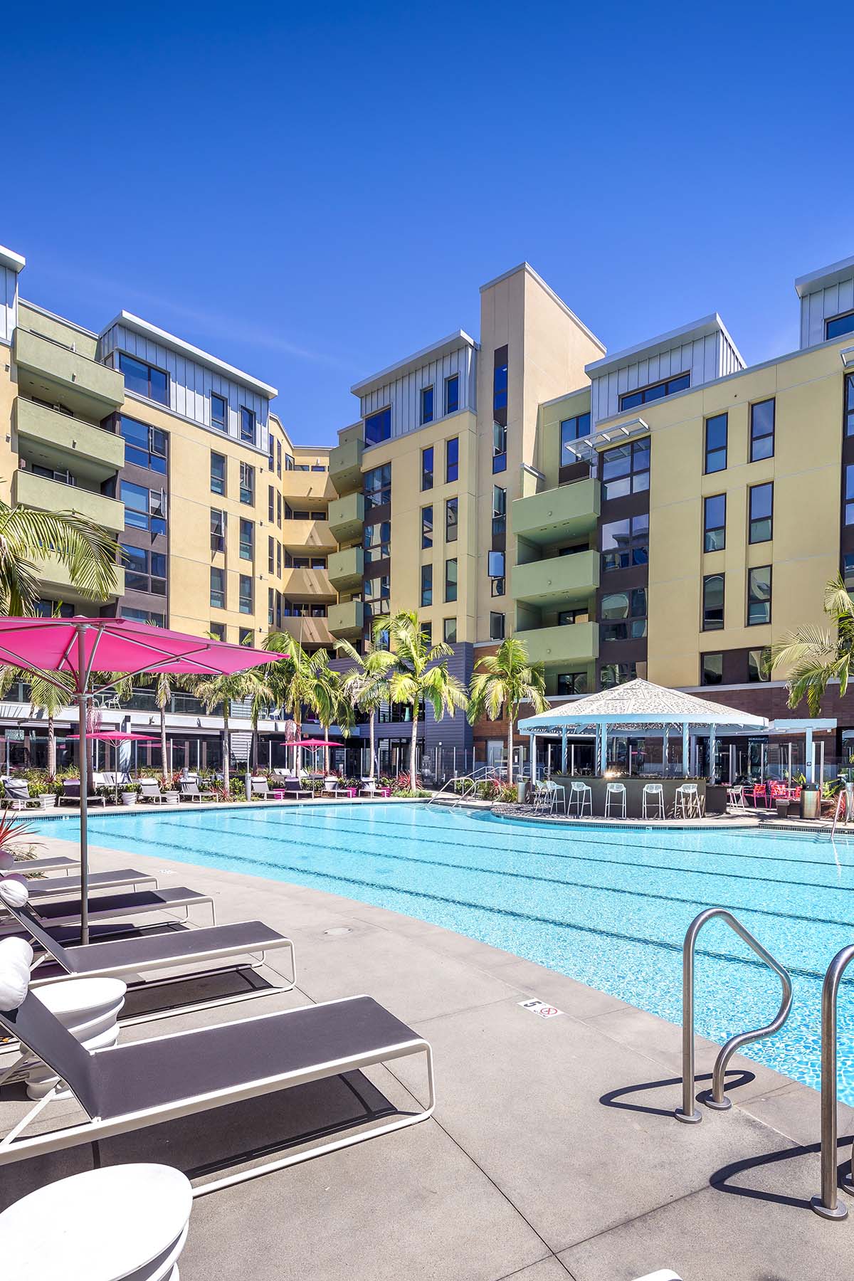 A pool area with sun loungers and a building in the background.