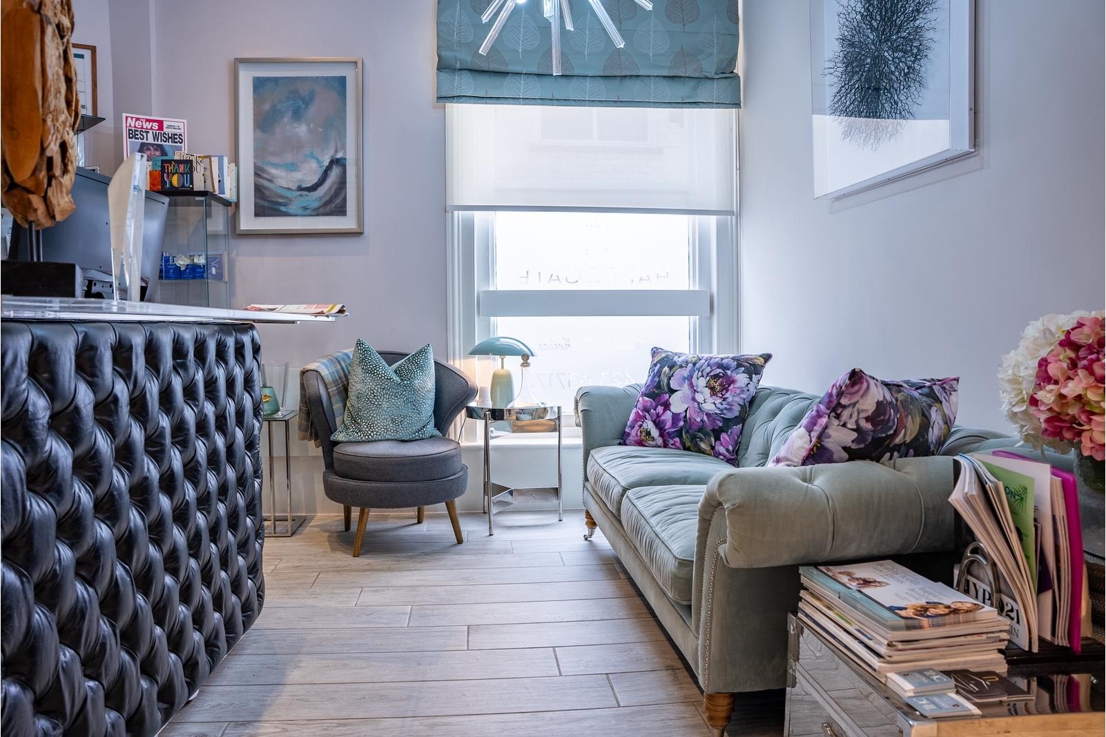 Welcoming reception and waiting area at The Harrogate Clinic featuring a tufted reception desk, plush velvet sofa, contemporary artwork, and fresh flowers, creating a relaxing first impression for dental and aesthetic patients in Harrogate.