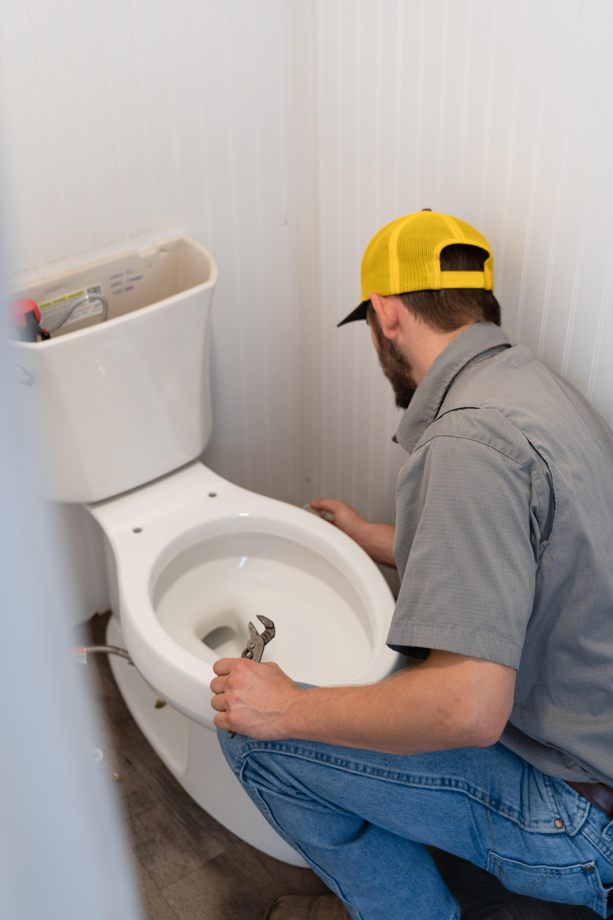 A skilled plumber from Tioga Contractors fixing a toilet in the Euless, TX area.