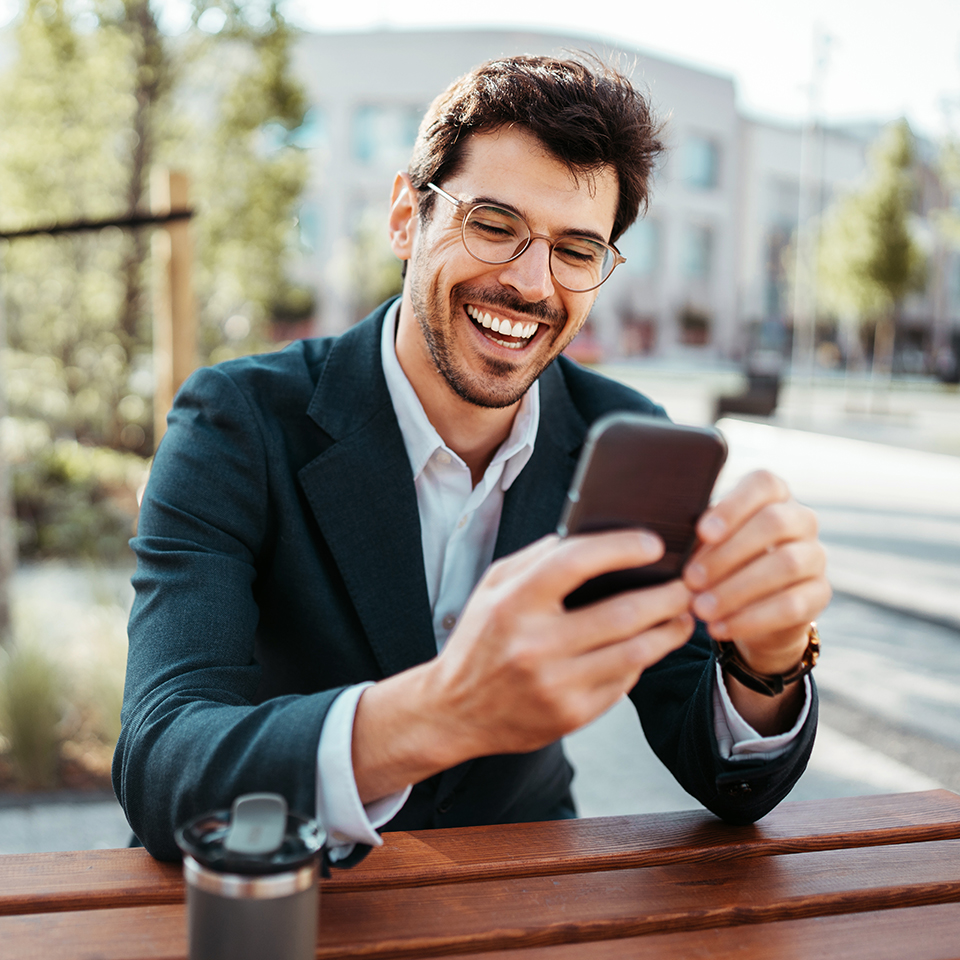 Man sitting at a table outside looking at a phone