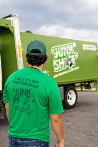 An over-the-shoulder view of a crew member wearing a green t-shirt that displays the slogan 