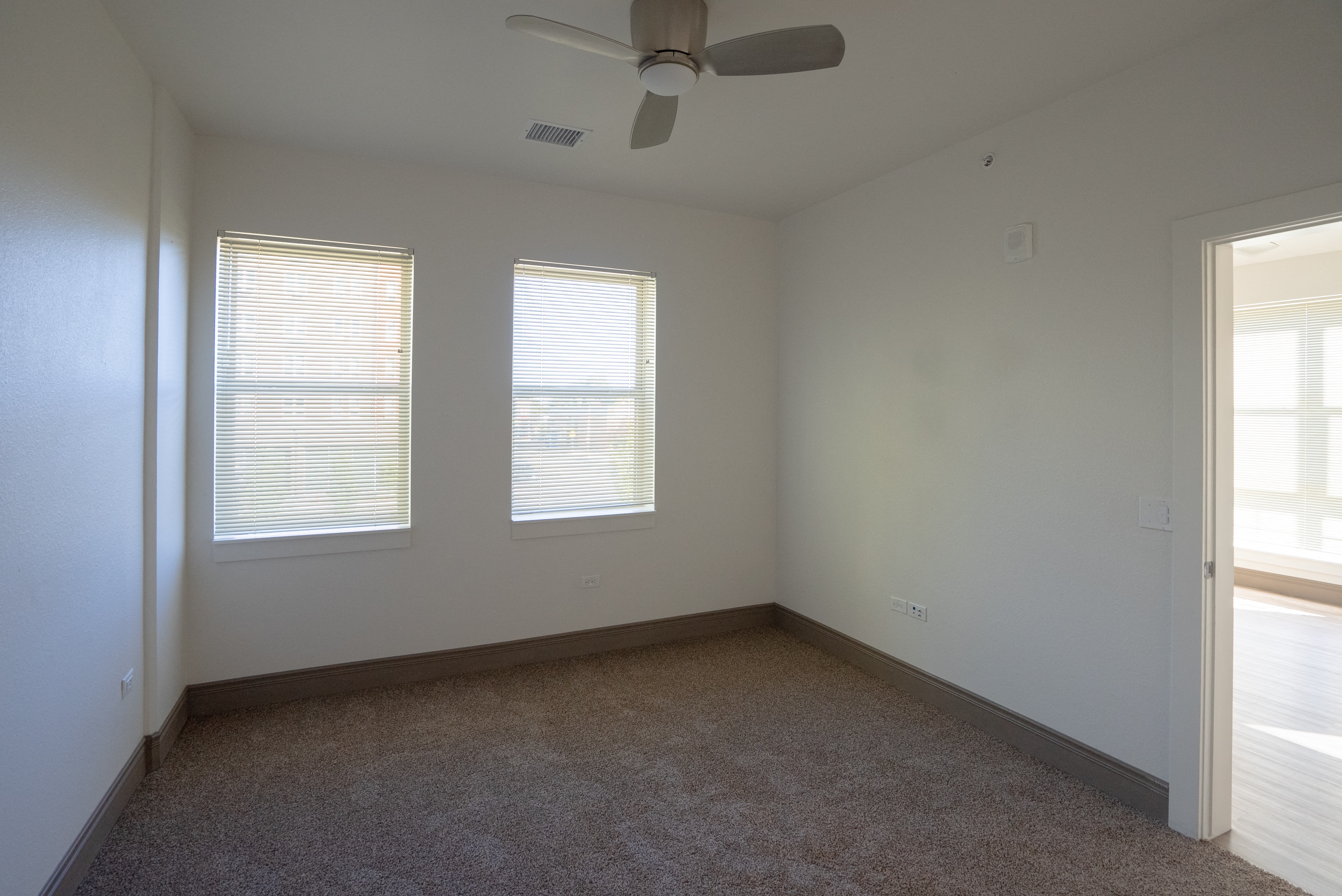 A room with a ceiling fan and carpeted floor.