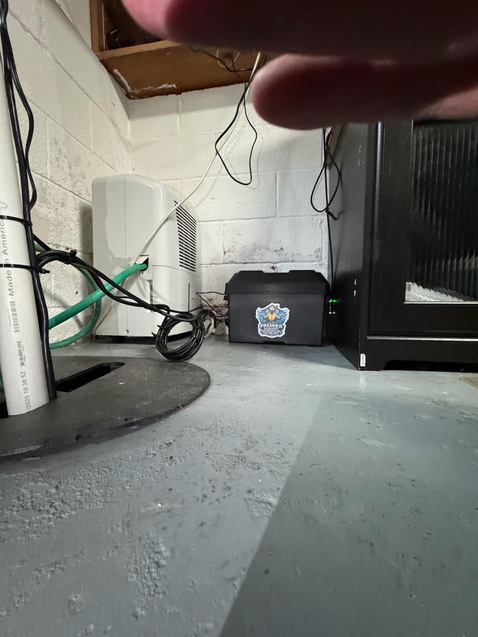 Photo of a clean basement floor and wall area after waterproofing work, showing plumbing, utility lines, and a dry interior space.