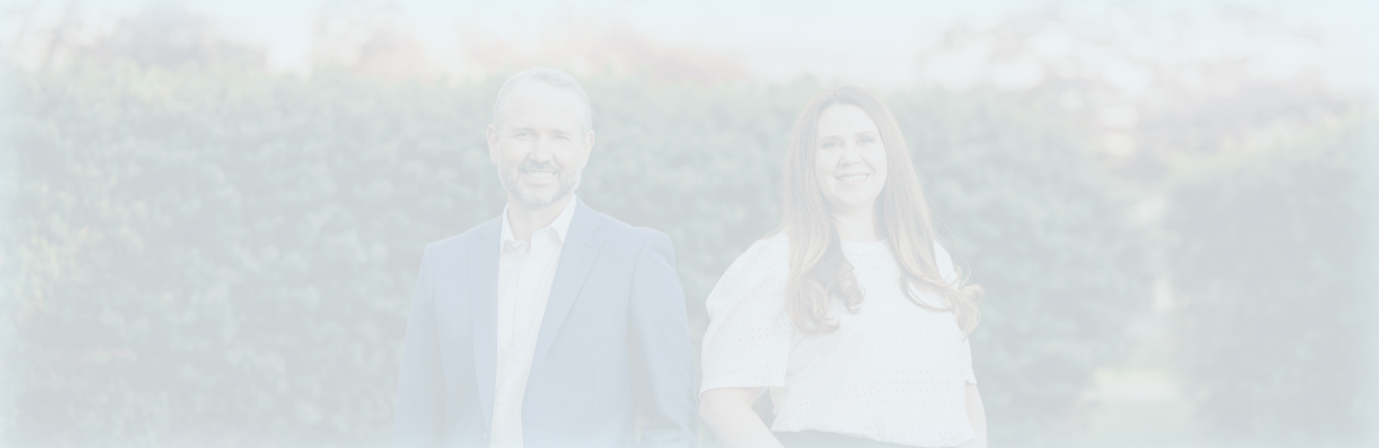 Jordan Anderson and Anastasiia Razmiasova standing together in front of a hedge.