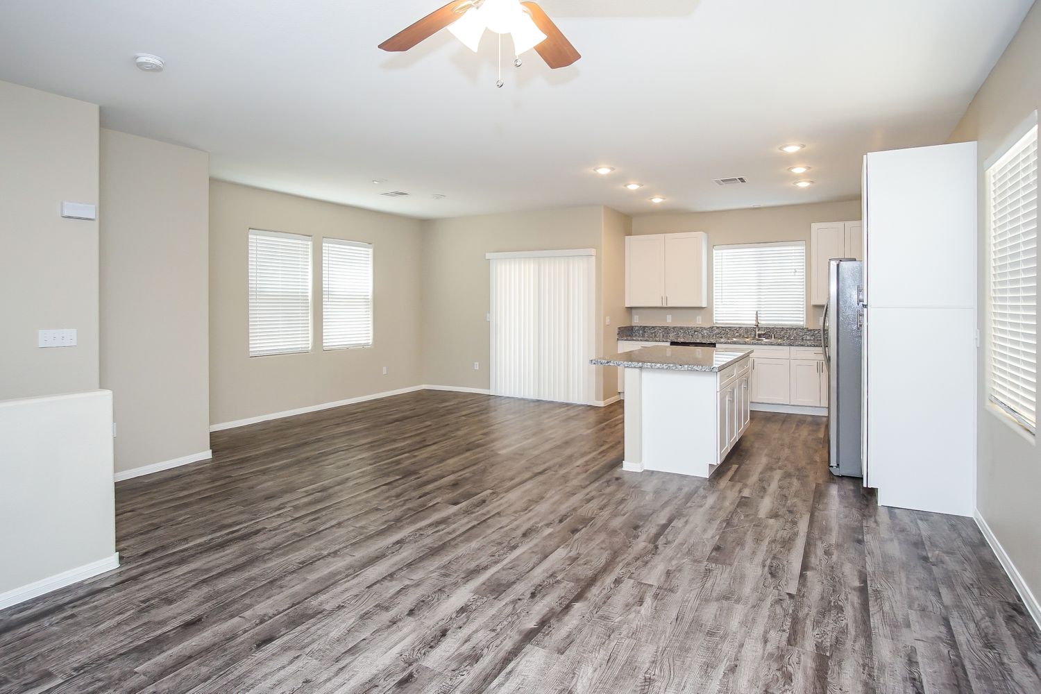 Kitchen and dining area featuring luxury vinyl plank flooring, granite countertops, an island and white cabinetry at Invitation Homes Las Vegas.