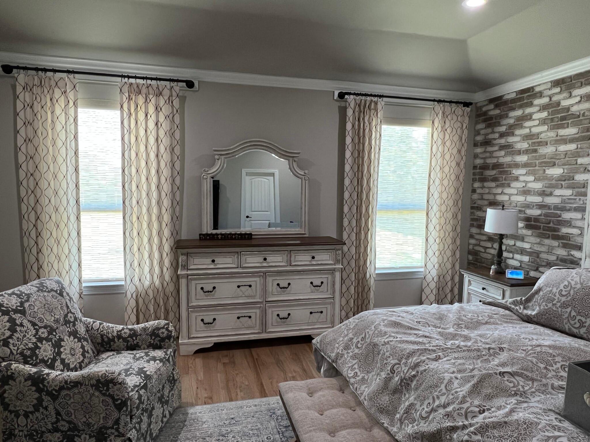 Light filtering, cordless roller shades paired with textured drapery is the perfect combo for a master bedroom. Our team at Budget Blinds of Rockwall, Terrell, and Greenville love the color combo our client chose for their Nevada, TX home.