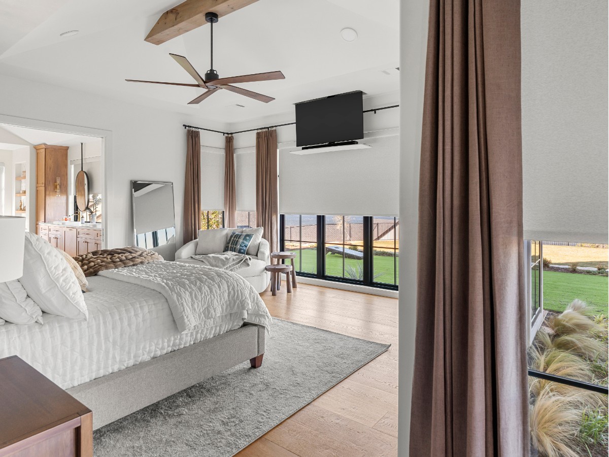 A layered look with Enlightened Styles Roller Shades and Carole Fabrics Drapery adds both style and privacy to this bedroom, creating a cozy and comfortable retreat.