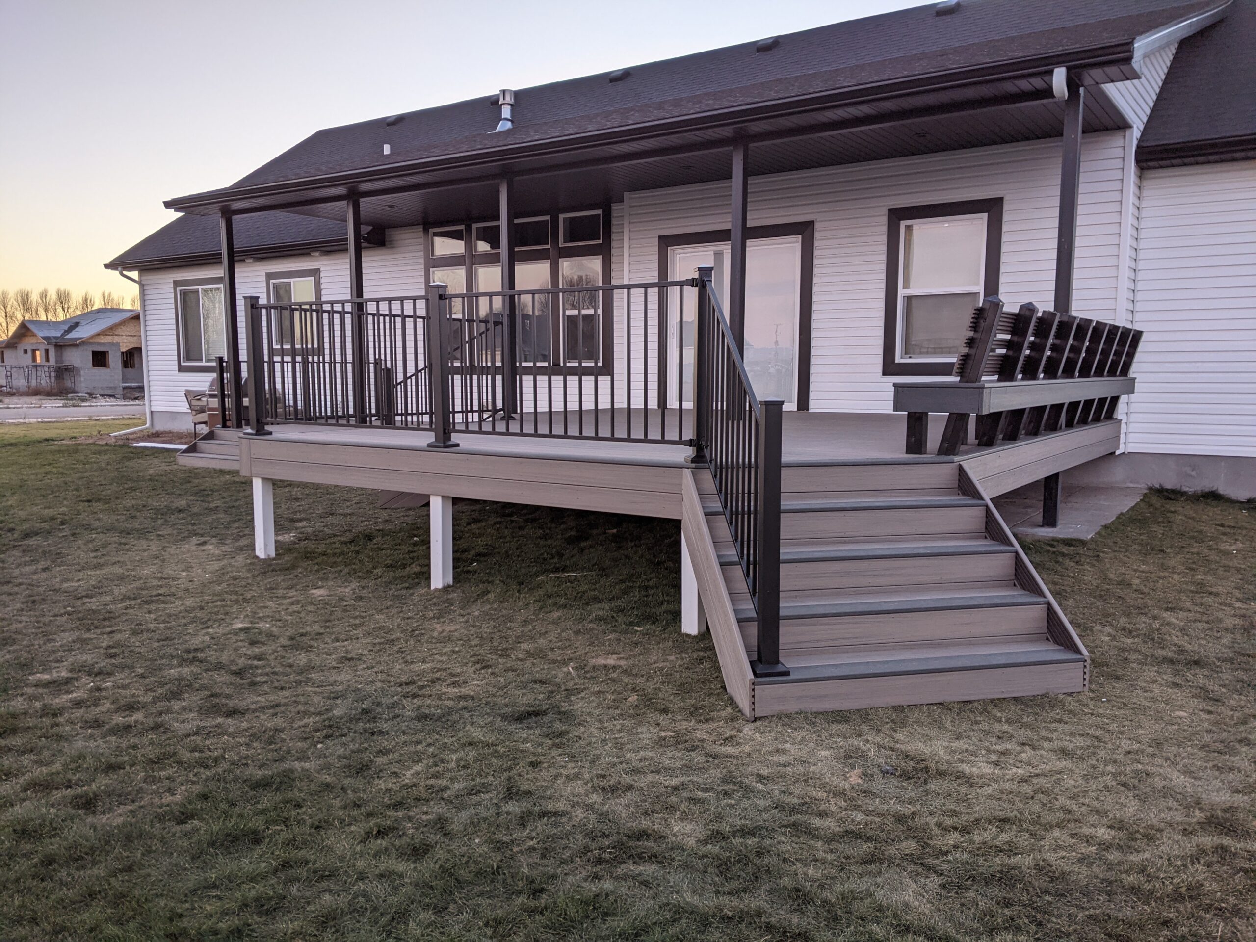 Enjoy outdoor living rain or shine with this versatile covered composite deck by DeckPro LLC. The design features a custom built-in bench for ample seating and sleek black metal railing for a modern finish.
