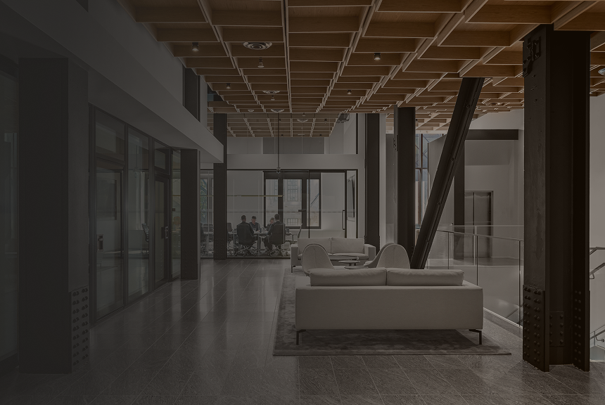 Lounge area in the Ascendant Wealth Partners office with a view of four colleagues meeting in a glass-walled conference room.