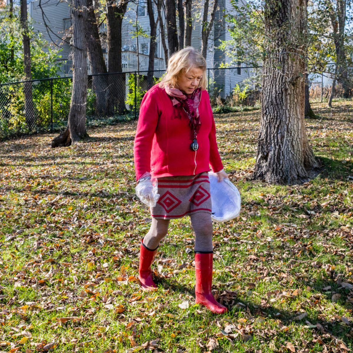 ScoopyPoo team member walks across a residential backyard carrying cleanup supplies, preparing to provide dependable pet waste removal while maintaining clean outdoor spaces for homeowners and their beloved dogs.