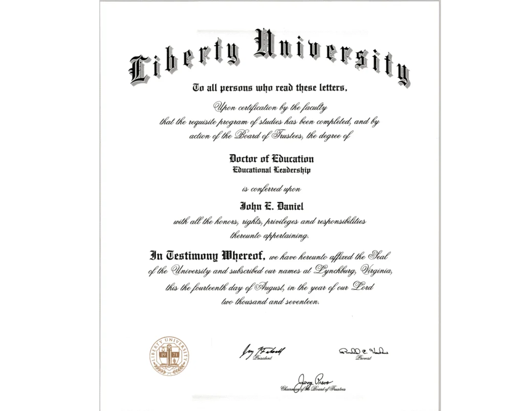 A diploma from Liberty University is shown in the image, with ornate script and official seals. The diploma states that John E. Daniel has been awarded a Doctor of Education in Educational Leadership. The document is dated the fourteenth day of August in the year of our Lord two thousand and seventeen. Signatures and seals of university officials are present at the bottom.