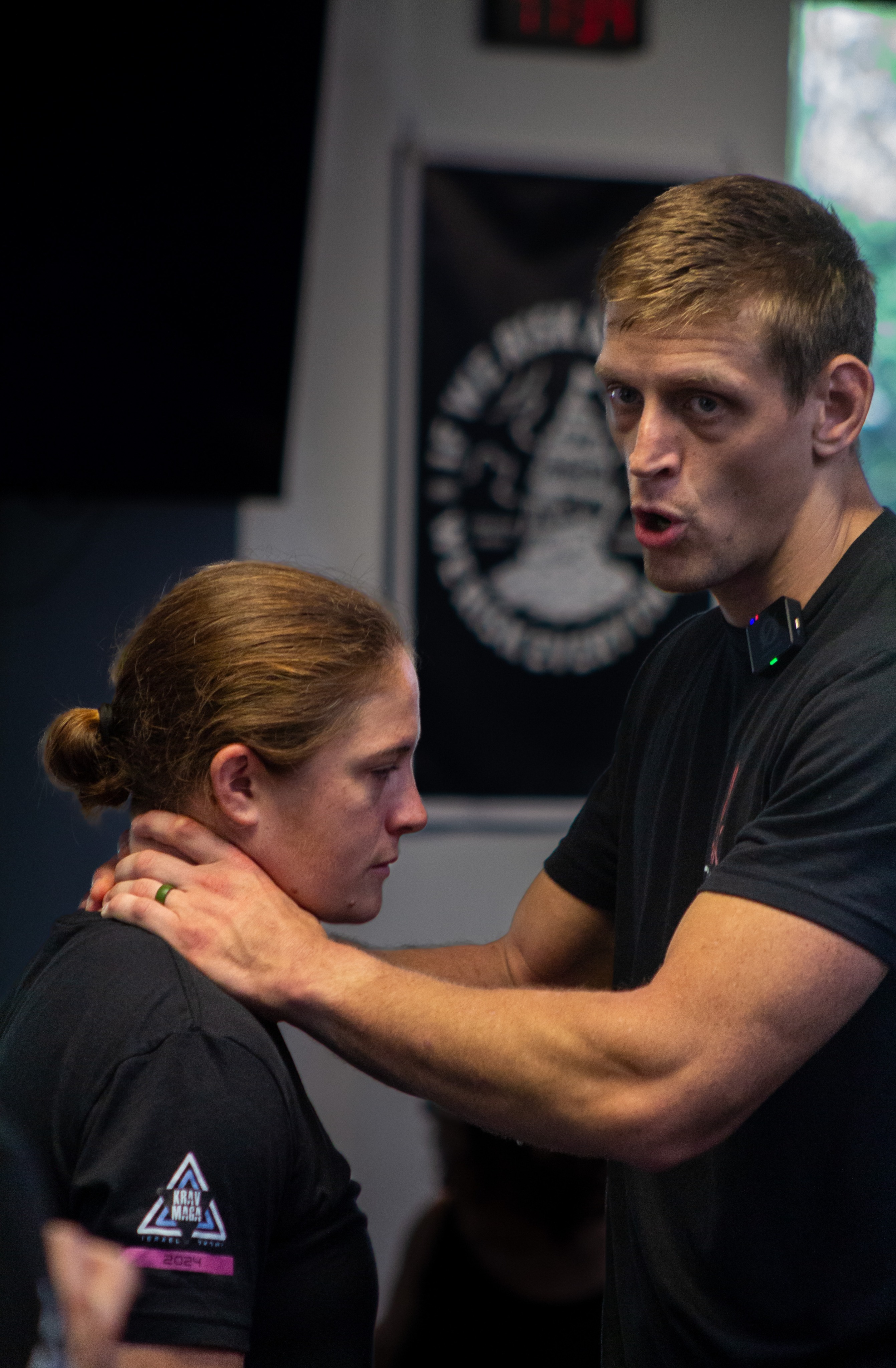 An instructor demonstrating a close-range neck control on a training partner during an adult Krav Maga class.