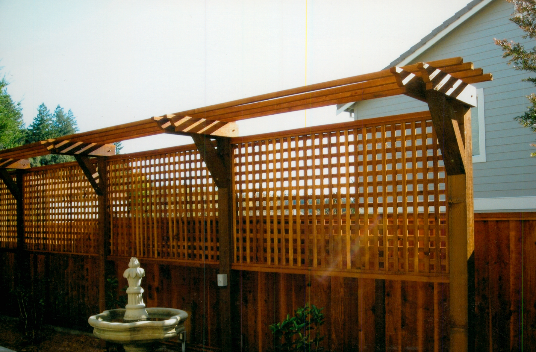 Custom wood pergola with lattice panels, creating a shaded outdoor living feature with added privacy.
